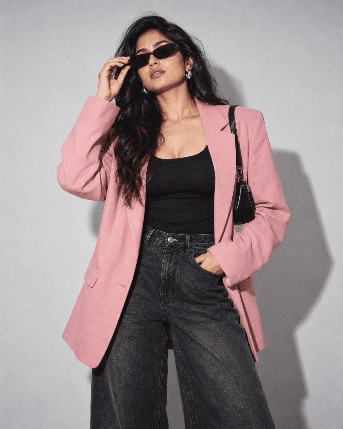 A pink blazer, black denim and silver jewellery styled together